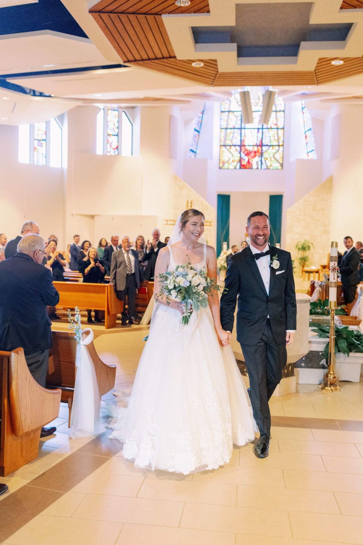 Happy newlyweds walking down the aisle after their church wedding ceremony at The Vinoy St. Petersburg with floral arrangements by Lemon Drops Weddings and Events
