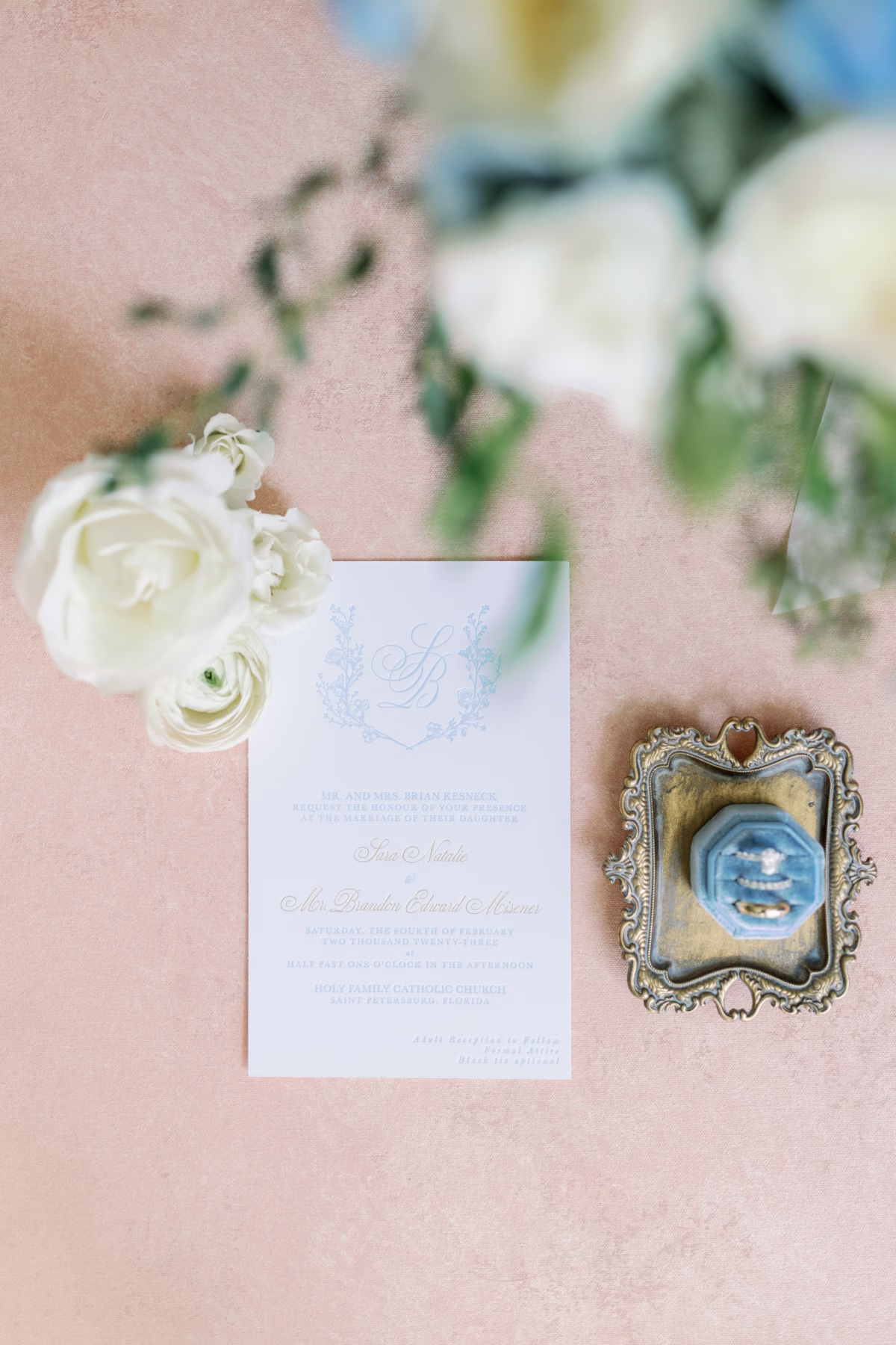 Elegant wedding invitation by Urban Coast Stationery with white ranunculus florals by Lemon Drops Weddings and Events and wedding rings in ornate frame at The Vinoy St. Petersburg waterfront wedding