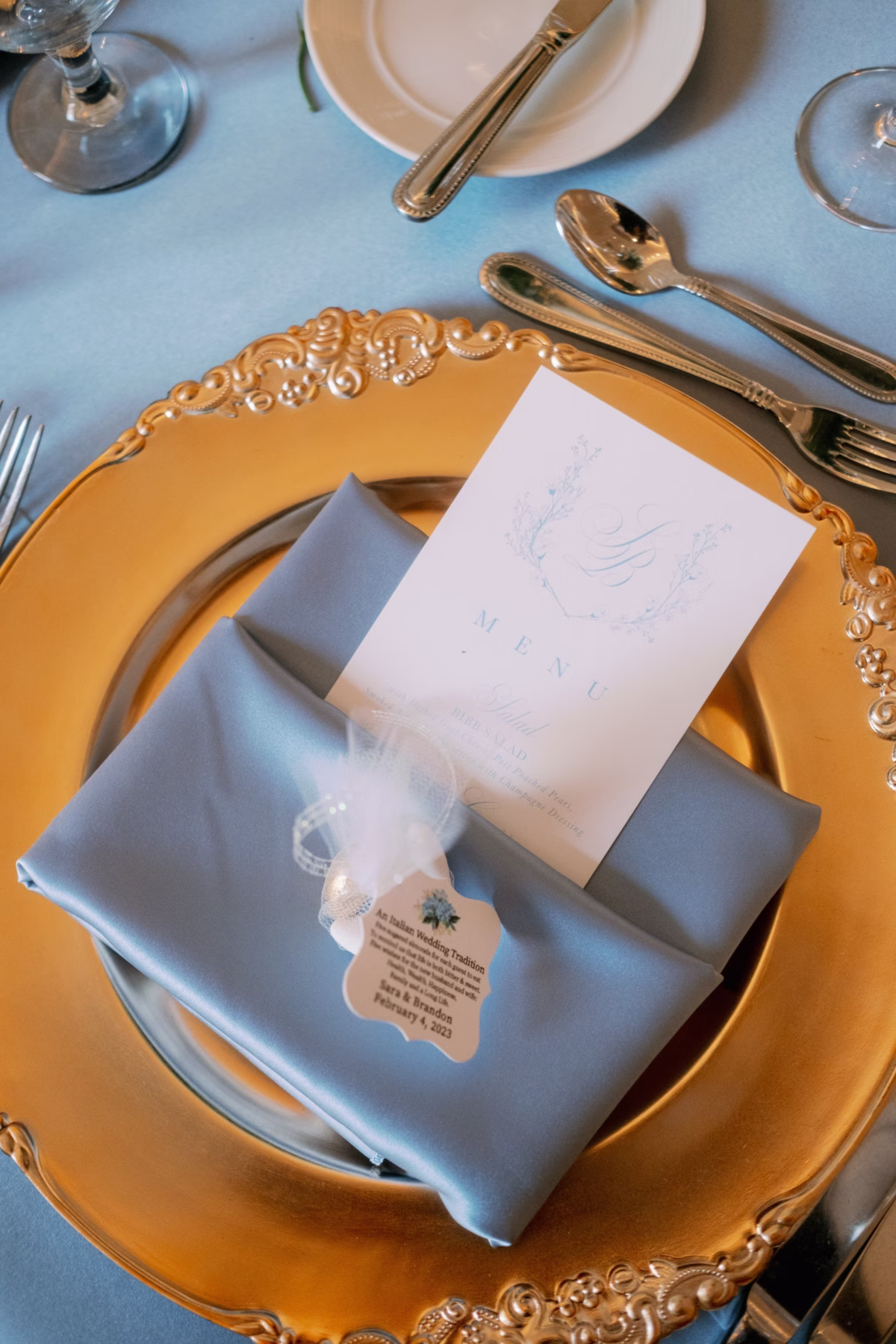 Elegant gold charger plate with blue silk napkin and custom menu card by Urban Coast stationery at The Vinoy St. Petersburg waterfront wedding planned by Lemon Drops Weddings and Events