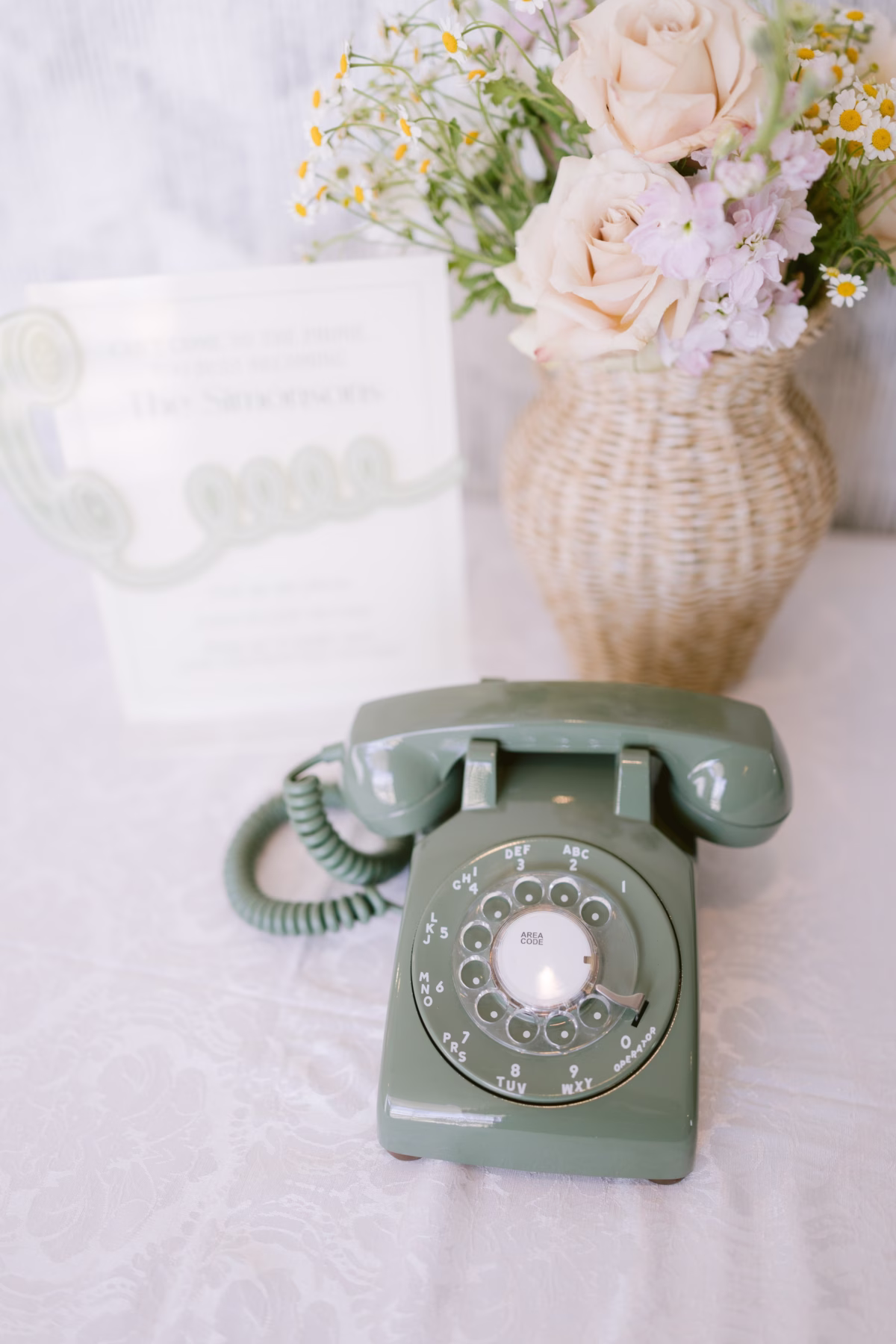 Vintage mint green rotary telephone with soft floral arrangement featuring blush roses and white flowers at Armature Works Tampa wedding photographed by Ashley Izquierdo Photography