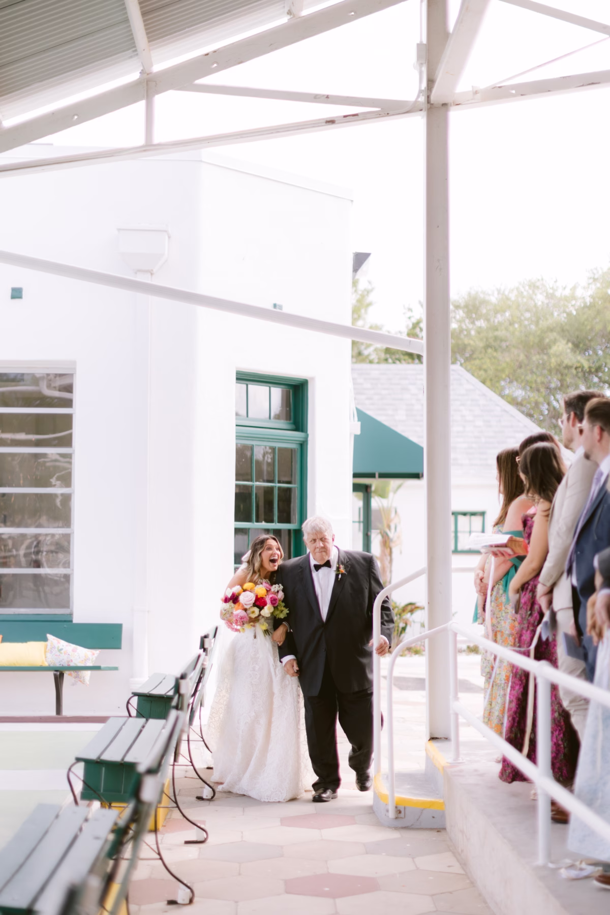 Bride walks down the aisle with father during outdoor wedding ceremony at St Pete Shuffleboard Club coordinated by Day of Details