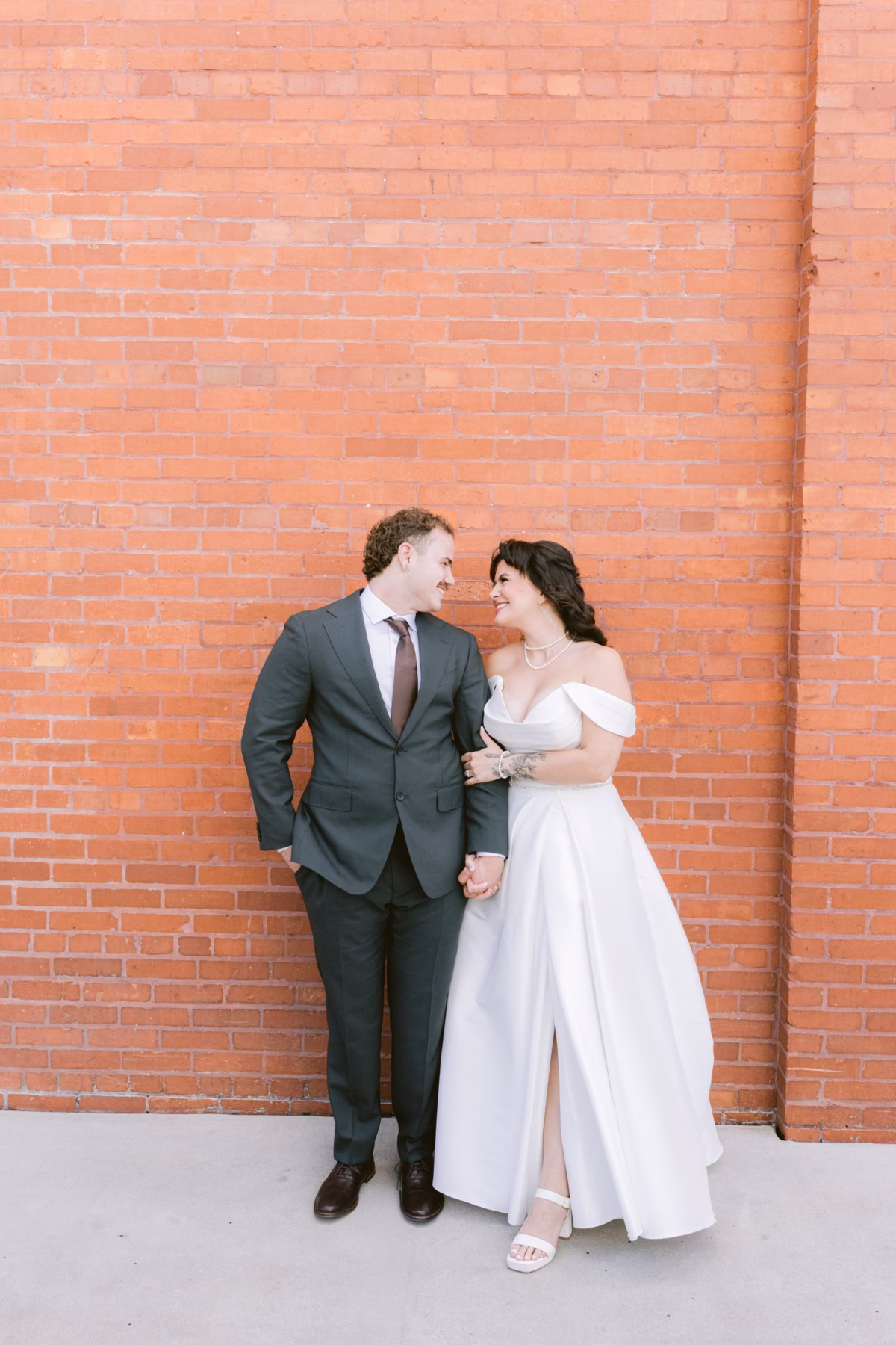 Bride and groom pose against brick wall at Armature Works Tampa wedding planned by Seashine Weddings and photographed by Ashley Izquierdo Photography
