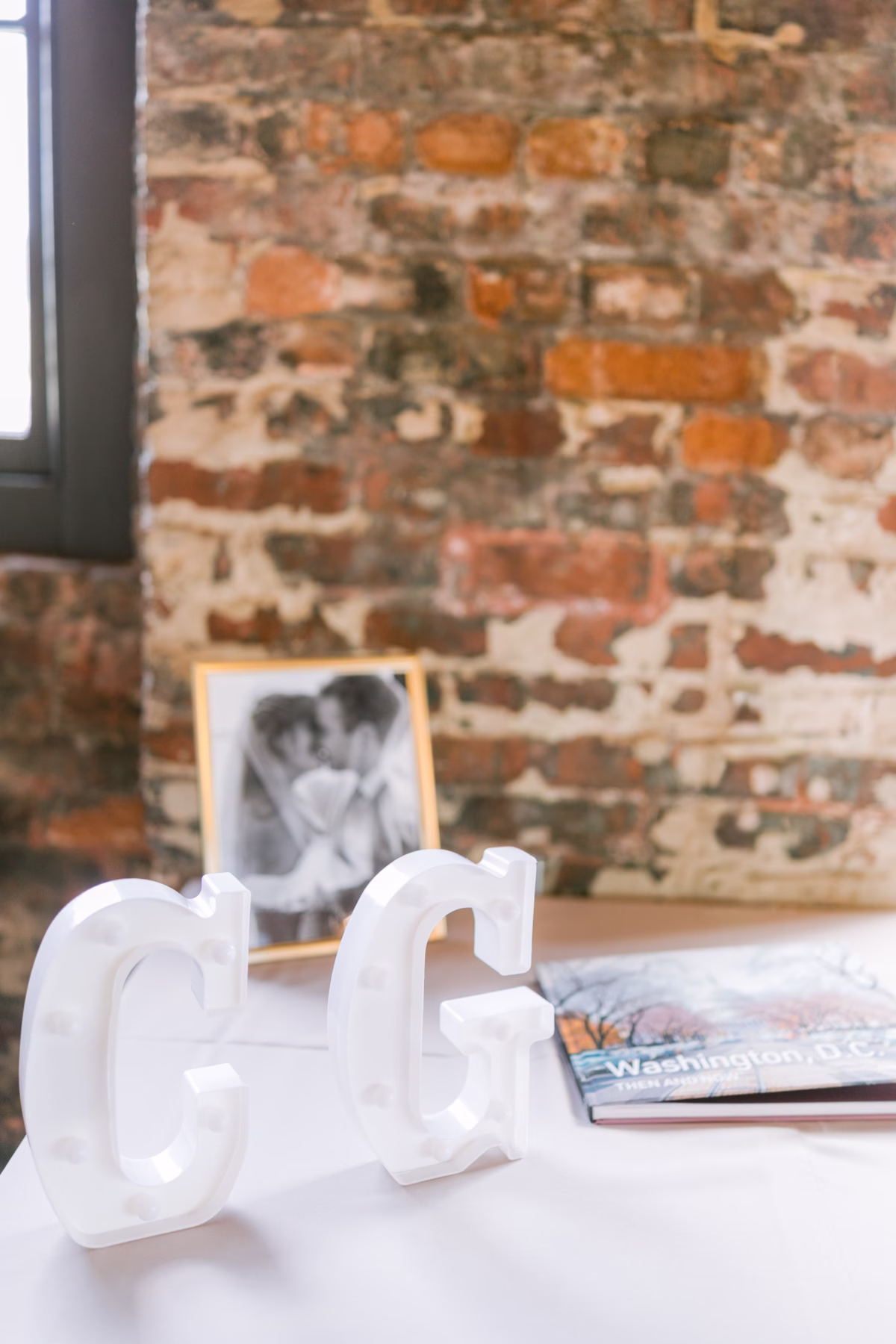 White acrylic wedding signage and black and white photo display on table at Armature Works Tampa wedding planned by Seashine Weddings