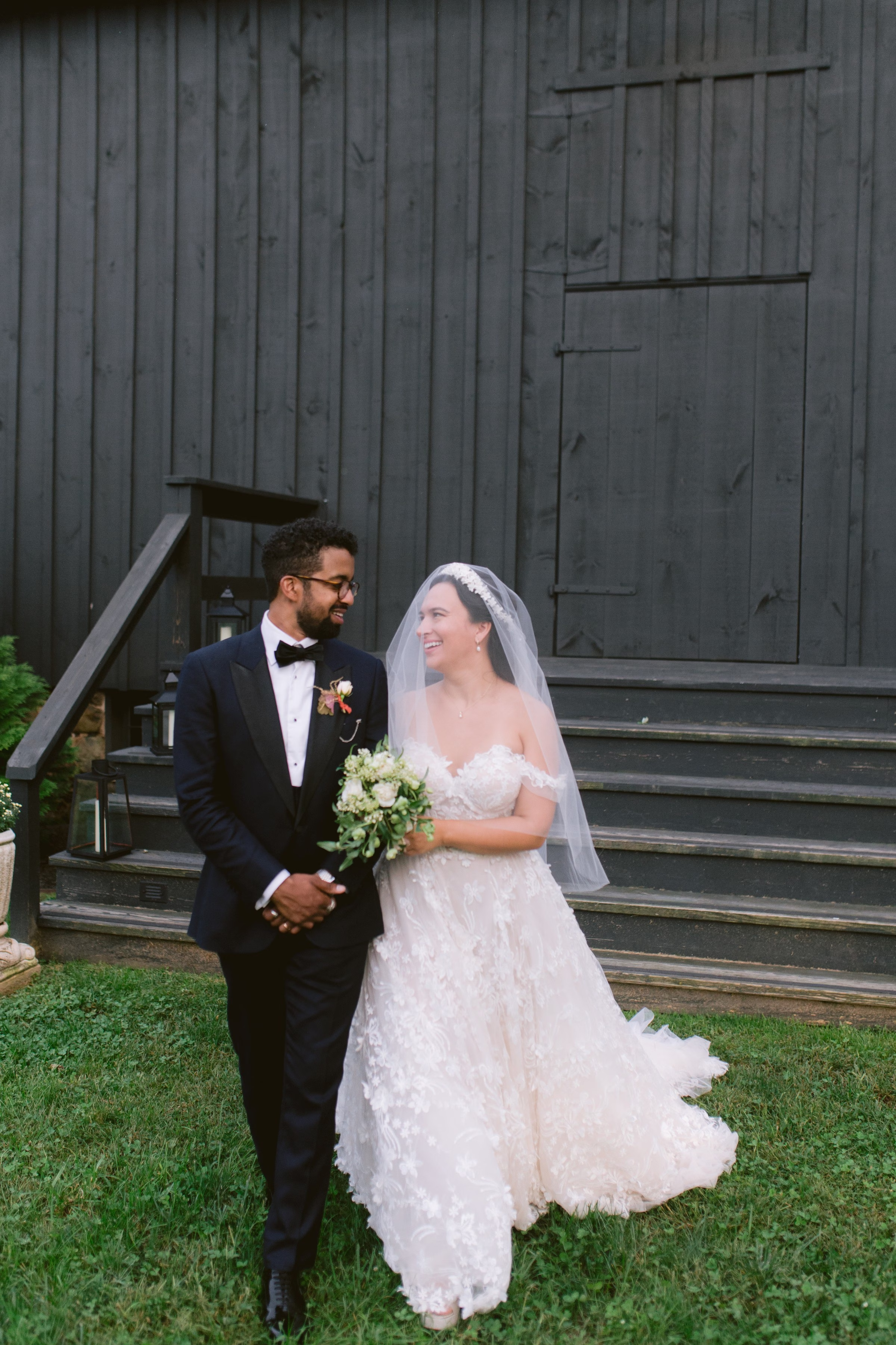 Bride and groom walking together at rustic barn wedding venue captured by Ashley Izquierdo Photography