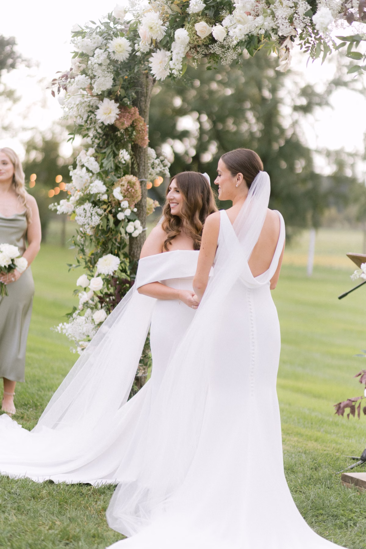 wedding planning olive and shae johnsons locust hall ceremony - A Farm Wedding at Johnson's Locust Hall, New Jersey Two brides share an intimate ceremony moment under a lush white floral arch at Johnson's Locust Hall farm wedding planned by Olive and Shae with florals by Allie Johnson