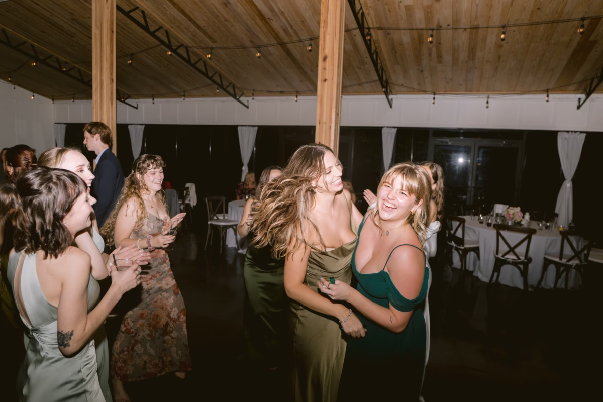 Wedding guests dancing and celebrating at indoor reception at Soire Estate in Tampa with wooden ceiling and string lights