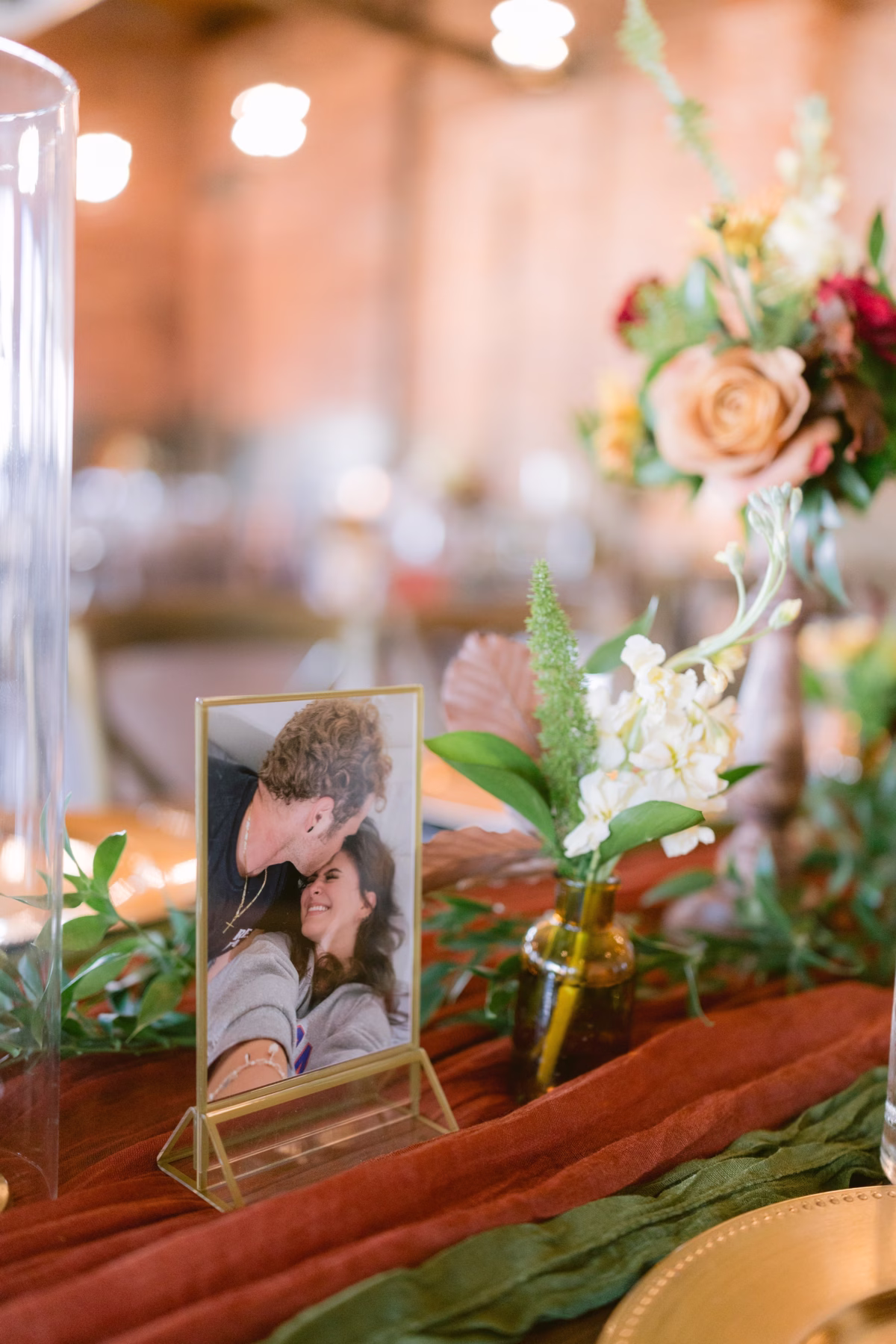 Wedding reception table decor featuring framed couple photo and floral arrangements by Events in Bloom at Armature Works Tampa