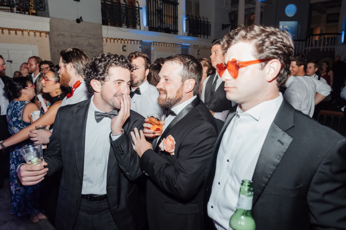Groomsmen in tuxedos enjoying cocktails at elegant wedding reception at The Lightner Museum coordinated by Coastal Celebrations
