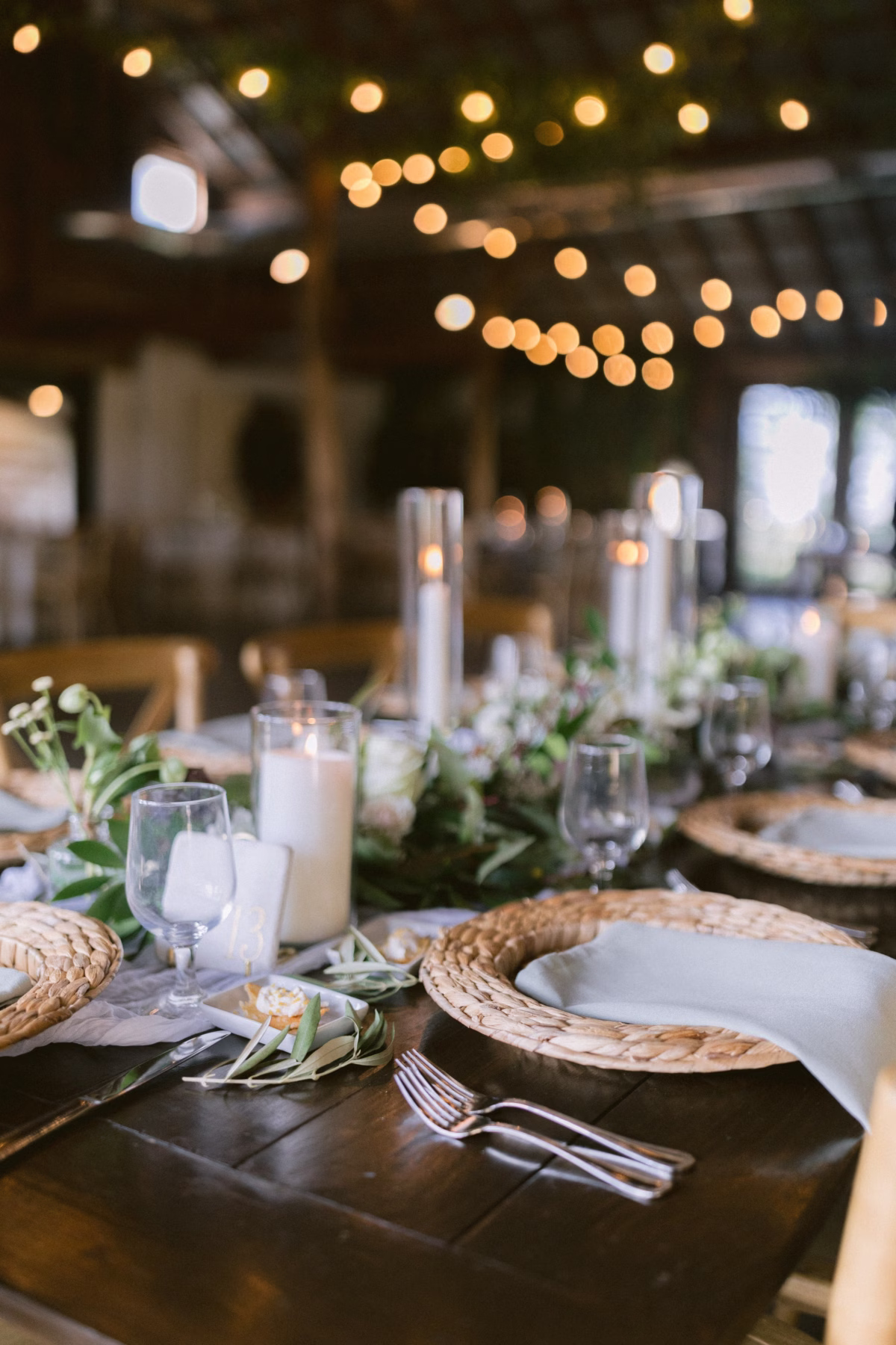 wedding reception tablescape allie johnson florist johnsons locust hall - A Farm Wedding at Johnson's Locust Hall, New Jersey Rustic wedding reception tablescape with woven chargers, white linens, and greenery centerpieces by Allie Johnson at Johnson's Locust Hall farm wedding venue in New Jersey