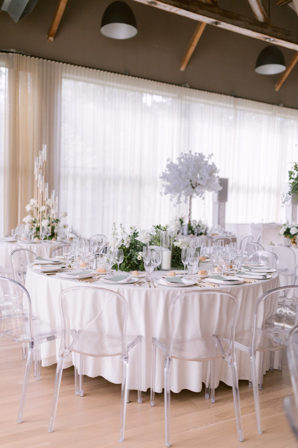 Elegant white wedding reception tablescape with tall floral centerpieces by Maky The Diva Flowers at The Roundhouse Beacon venue in Hudson Valley