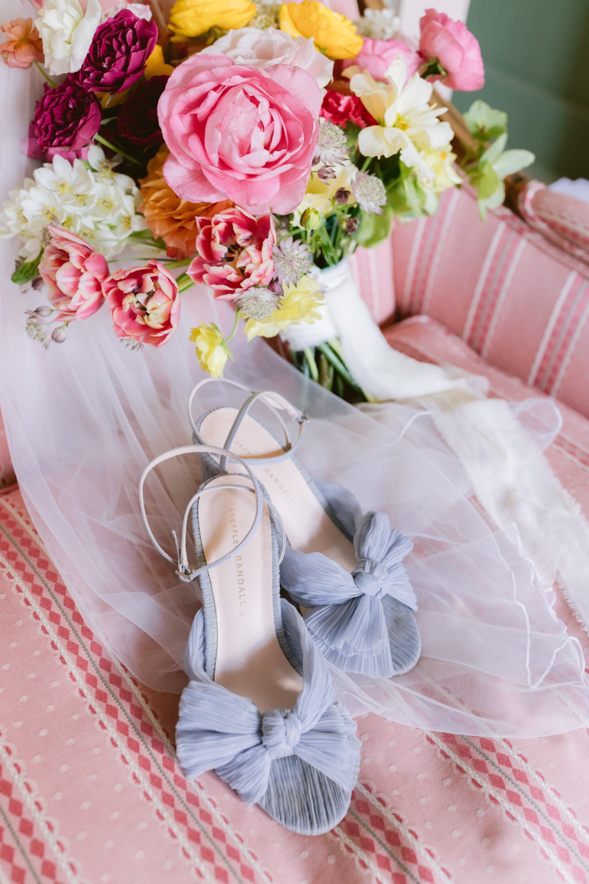Blue wedding shoes with bow details alongside colorful bridal bouquet by Petite Fleur at St Pete Shuffleboard Club wedding