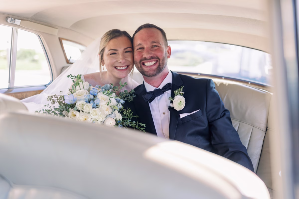 Bride and groom sitting in vintage wedding car by Revvies Transportation at The Vinoy St. Petersburg waterfront wedding