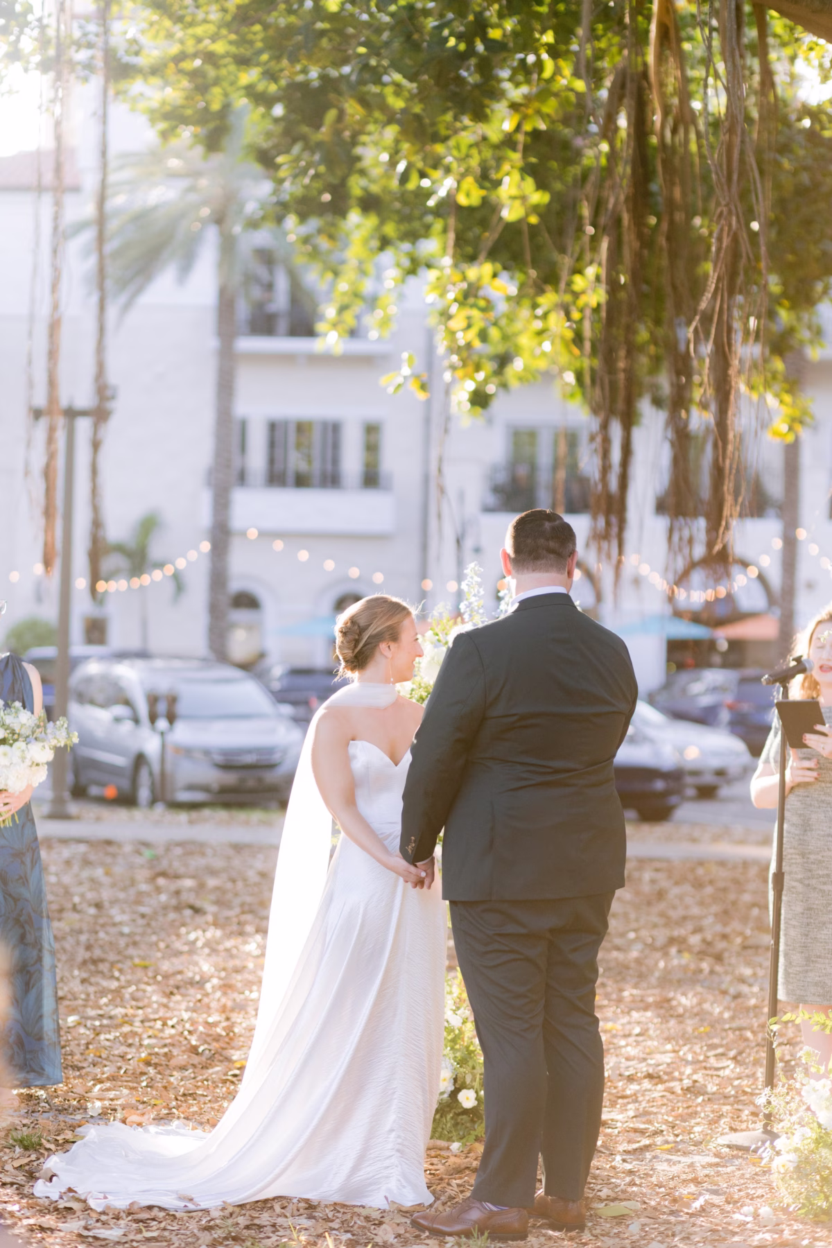 Bride and groom hold hands during outdoor wedding ceremony with floral arrangements by Wonderland Floral Art at art museum wedding in St. Petersburg